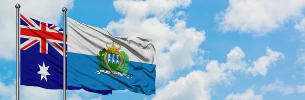 Bandera de Australia y San Marino ondeando en el viento contra el cielo azul nublado blanco juntos. Concepto diplomático, relaciones internacionales . —  Fotos de Stock