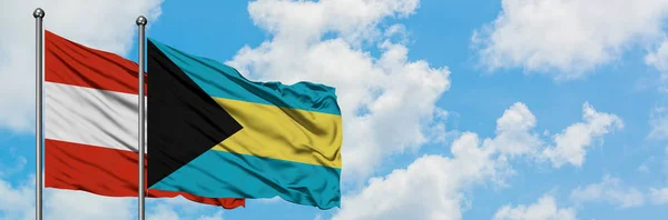 Bandera de Austria y Bahamas ondeando en el viento contra el cielo azul nublado blanco juntos. Concepto diplomático, relaciones internacionales . —  Fotos de Stock