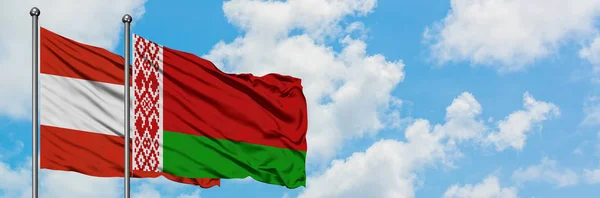 Bandera de Austria y Bielorrusia ondeando en el viento contra el cielo azul nublado blanco juntos. Concepto diplomático, relaciones internacionales . — Foto de Stock