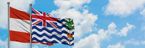 Bandera de Austria y del Territorio Británico del Océano Índico ondeando en el viento contra el cielo azul nublado blanco juntos. Concepto diplomático, relaciones internacionales . — Foto de Stock