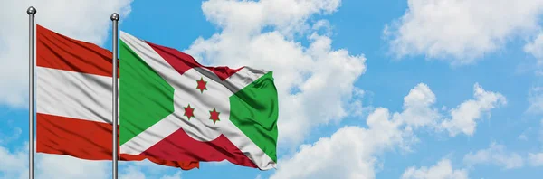 Bandera de Austria y Burundi ondeando en el viento contra el cielo azul nublado blanco juntos. Concepto diplomático, relaciones internacionales . — Foto de Stock