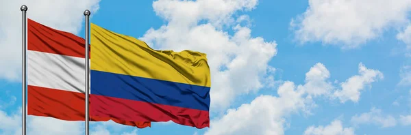 Bandera de Austria y Colombia ondeando en el viento contra el cielo azul nublado blanco juntos. Concepto diplomático, relaciones internacionales . — Foto de Stock