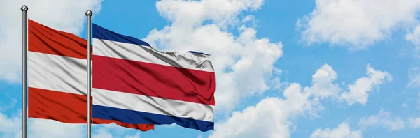 Австрия и Коста-Рика вместе размахивают флагом на ветру против белого облачного голубого неба. Концепция дипломатии, международные отношения . — стоковое фото