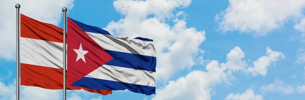 A bandeira da Áustria e Cuba agitando no vento contra o céu azul nublado branco juntos. Conceito de diplomacia, relações internacionais . — Fotografia de Stock