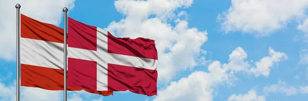 白い曇り青空に向かう風に揺るぐオーストリアとデンマークの旗。外交概念、国際関係. — ストック写真