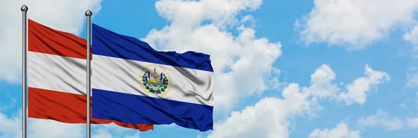 Bandera de Austria y El Salvador ondeando en el viento contra el cielo azul nublado blanco juntos. Concepto diplomático, relaciones internacionales . — Foto de Stock