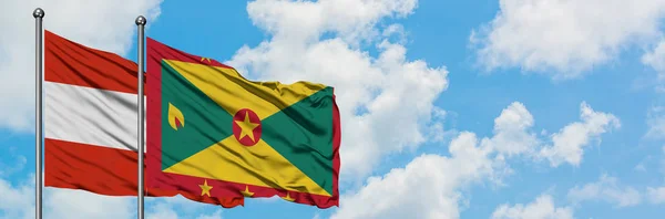 Österreich und die Grenada-Flagge wehen gemeinsam im Wind gegen den wolkenverhangenen blauen Himmel. Diplomatie-Konzept, internationale Beziehungen. — Stockfoto