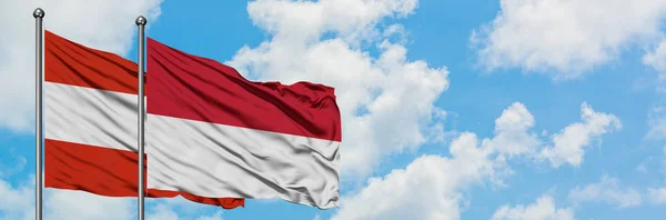 Ausztria és Indonézia zászló integetett a szél ellen, fehér felhős kék ég együtt. Diplomáciai koncepció, nemzetközi kapcsolatok. — Stock Fotó