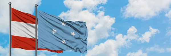 Áustria e Micronésia bandeira acenando no vento contra o céu azul nublado branco juntos. Conceito de diplomacia, relações internacionais . — Fotografia de Stock
