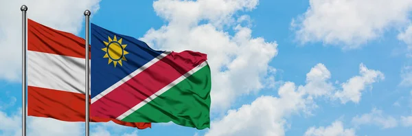 Oostenrijk en Namibië vlag zwaaien in de wind tegen witte bewolkte blauwe hemel samen. Diplomatie concept, internationale betrekkingen. — Stockfoto