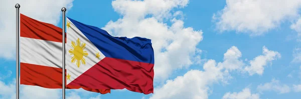 A bandeira da Áustria e Filipinas agitando no vento contra o céu azul nublado branco juntos. Conceito de diplomacia, relações internacionais . — Fotografia de Stock