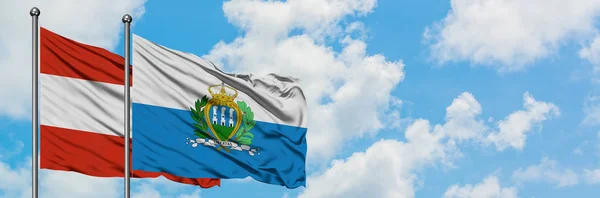 Avusturya ve San Marino bayrağı birlikte beyaz bulutlu mavi gökyüzüne karşı rüzgarda sallayarak. Diplomasi kavramı, uluslararası ilişkiler. — Stok fotoğraf