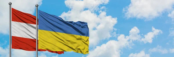 Bandera de Austria y Ucrania ondeando en el viento contra el cielo azul nublado blanco juntos. Concepto diplomático, relaciones internacionales . — Foto de Stock