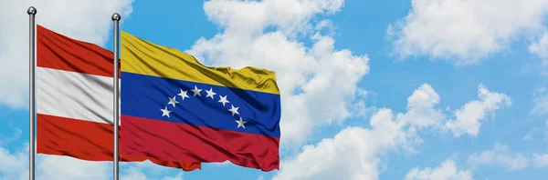 Ausztria és Venezuela zászló integetett a szél ellen, fehér felhős kék eget együtt. Diplomáciai koncepció, nemzetközi kapcsolatok. — Stock Fotó
