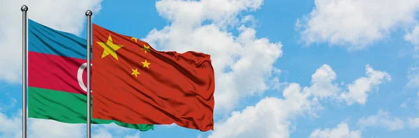 Aserbajdsjan og Kina flag vinker i vinden mod hvid overskyet blå himmel sammen. Diplomati koncept, internationale relationer . - Stock-foto