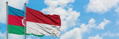 Azerbaycan ve Monako bayrağı havada havada sallayarak beyaz bulutlu mavi gökyüzüne karşı birlikte. Diplomasi kavramı, uluslararası ilişkiler.