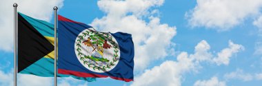 Bahamalar ve Belize bayrağı birlikte beyaz bulutlu mavi gökyüzüne karşı rüzgarda sallayarak. Diplomasi kavramı, uluslararası ilişkiler.