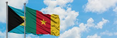 Bahamalar ve Kamerun bayrağı birlikte beyaz bulutlu mavi gökyüzüne karşı rüzgarda sallayarak. Diplomasi kavramı, uluslararası ilişkiler.