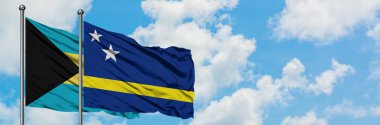 Bahamalar ve Curacao bayrağı birlikte beyaz bulutlu mavi gökyüzüne karşı rüzgarda sallayarak. Diplomasi kavramı, uluslararası ilişkiler.