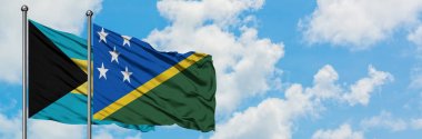Bahamalar ve Solomon Adaları bayrağı birlikte beyaz bulutlu mavi gökyüzüne karşı rüzgarda sallayarak. Diplomasi kavramı, uluslararası ilişkiler.