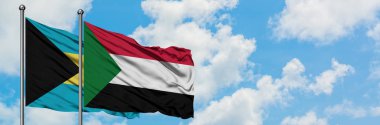 Bahamalar ve Sudan bayrağı birlikte beyaz bulutlu mavi gökyüzüne karşı rüzgarda sallayarak. Diplomasi kavramı, uluslararası ilişkiler.