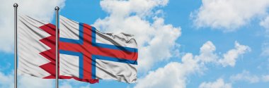Bahreyn ve Faroe Adaları bayrağı birlikte beyaz bulutlu mavi gökyüzüne karşı rüzgarda sallayarak. Diplomasi kavramı, uluslararası ilişkiler.