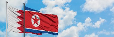 Bahreyn ve Kuzey Kore bayrağı birlikte beyaz bulutlu mavi gökyüzüne karşı rüzgarsal sallayarak. Diplomasi kavramı, uluslararası ilişkiler.