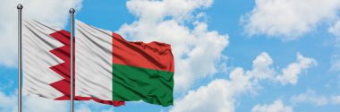 Bahreyn ve Madagaskar bayrağı birlikte beyaz bulutlu mavi gökyüzüne karşı rüzgarda sallayarak. Diplomasi kavramı, uluslararası ilişkiler.