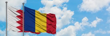 Bahreyn ve Romanya bayrağı birlikte beyaz bulutlu mavi gökyüzüne karşı rüzgarda sallayarak. Diplomasi kavramı, uluslararası ilişkiler.