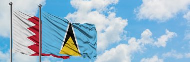 Bahreyn ve Saint Lucia bayrağı birlikte beyaz bulutlu mavi gökyüzüne karşı rüzgarda sallayarak. Diplomasi kavramı, uluslararası ilişkiler.