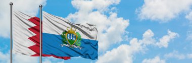 Bahreyn ve San Marino bayrağı birlikte beyaz bulutlu mavi gökyüzüne karşı rüzgarda sallayarak. Diplomasi kavramı, uluslararası ilişkiler.