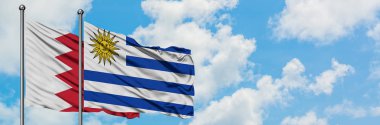 Bahreyn ve Uruguay bayrağı birlikte beyaz bulutlu mavi gökyüzüne karşı rüzgarsal sallayarak. Diplomasi kavramı, uluslararası ilişkiler.
