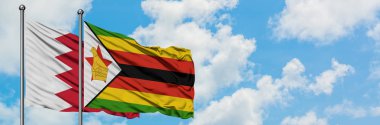 Bahreyn ve Zimbabve bayrağı birlikte beyaz bulutlu mavi gökyüzüne karşı rüzgarsal sallayarak. Diplomasi kavramı, uluslararası ilişkiler.