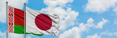 Beyaz Rusya ve Japonya bayrağı birlikte beyaz bulutlu mavi gökyüzüne karşı rüzgarda sallayarak. Diplomasi kavramı, uluslararası ilişkiler.