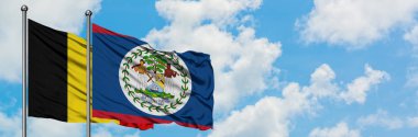 Belçika ve Belize bayrağı birlikte beyaz bulutlu mavi gökyüzüne karşı rüzgarda sallayarak. Diplomasi kavramı, uluslararası ilişkiler.