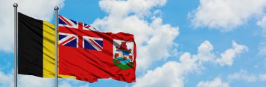 Belçika ve Bermuda bayrağı birlikte beyaz bulutlu mavi gökyüzüne karşı rüzgarda sallayarak. Diplomasi kavramı, uluslararası ilişkiler.