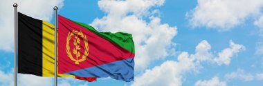 Belçika ve Eritre bayrağı birlikte beyaz bulutlu mavi gökyüzüne karşı rüzgarda sallayarak. Diplomasi kavramı, uluslararası ilişkiler.