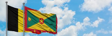 Belçika ve Grenada bayrağı birlikte beyaz bulutlu mavi gökyüzüne karşı rüzgarda sallayarak. Diplomasi kavramı, uluslararası ilişkiler.