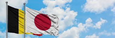 Belçika ve Japonya bayrağı birlikte beyaz bulutlu mavi gökyüzüne karşı rüzgarda sallayarak. Diplomasi kavramı, uluslararası ilişkiler.