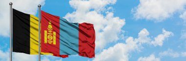 Belçika ve Moğolistan bayrağı birlikte beyaz bulutlu mavi gökyüzüne karşı rüzgarsal sallayarak. Diplomasi kavramı, uluslararası ilişkiler.