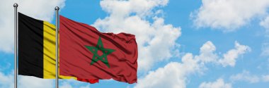 Belgium and Morocco flag waving in the wind against white cloudy blue sky together. Diplomacy concept, international relations. clipart