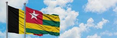 Belçika ve Togo bayrağı birlikte beyaz bulutlu mavi gökyüzüne karşı rüzgarda sallayarak. Diplomasi kavramı, uluslararası ilişkiler.
