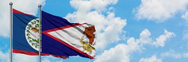 Belize ve Amerikan Samoa bayrağı birlikte beyaz bulutlu mavi gökyüzüne karşı rüzgarda sallayarak. Diplomasi kavramı, uluslararası ilişkiler.