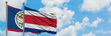 Belize ve Kosta Rika bayrağı birlikte beyaz bulutlu mavi gökyüzüne karşı rüzgarda sallayarak. Diplomasi kavramı, uluslararası ilişkiler.