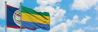 Belize ve Gabon bayrağı birlikte beyaz bulutlu mavi gökyüzüne karşı rüzgarda sallayarak. Diplomasi kavramı, uluslararası ilişkiler.