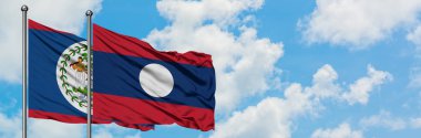 Belize ve Laos bayrağı birlikte beyaz bulutlu mavi gökyüzüne karşı rüzgarda sallayarak. Diplomasi kavramı, uluslararası ilişkiler.