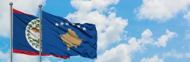 Belize ve Kosova bayrağı birlikte beyaz bulutlu mavi gökyüzüne karşı rüzgarda sallayarak. Diplomasi kavramı, uluslararası ilişkiler.