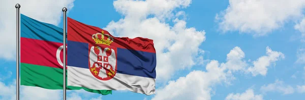 Bandera de Azerbaiyán y Serbia ondeando en el viento contra el cielo azul nublado blanco juntos. Concepto diplomático, relaciones internacionales . — Foto de Stock