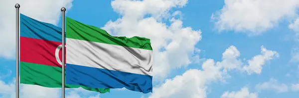 Bandera de Azerbaiyán y Sierra Leona ondeando en el viento contra el cielo azul nublado blanco juntos. Concepto diplomático, relaciones internacionales . — Foto de Stock