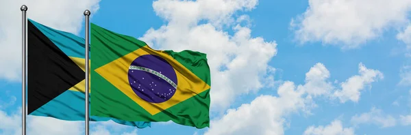 Bahamy a Brazilská vlajka mávali ve větru proti bíle zatažené modré obloze. Diplomacie, mezinárodní vztahy. — Stock fotografie